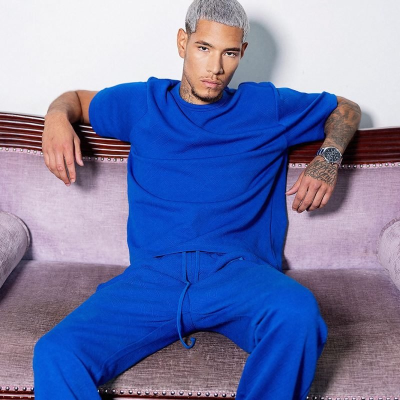 Fashion portrait of male model Juan Lopez wearing a vibrant blue two-piece outfit.